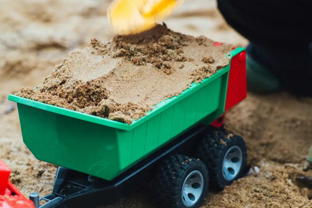 Child playing with truck in the sand